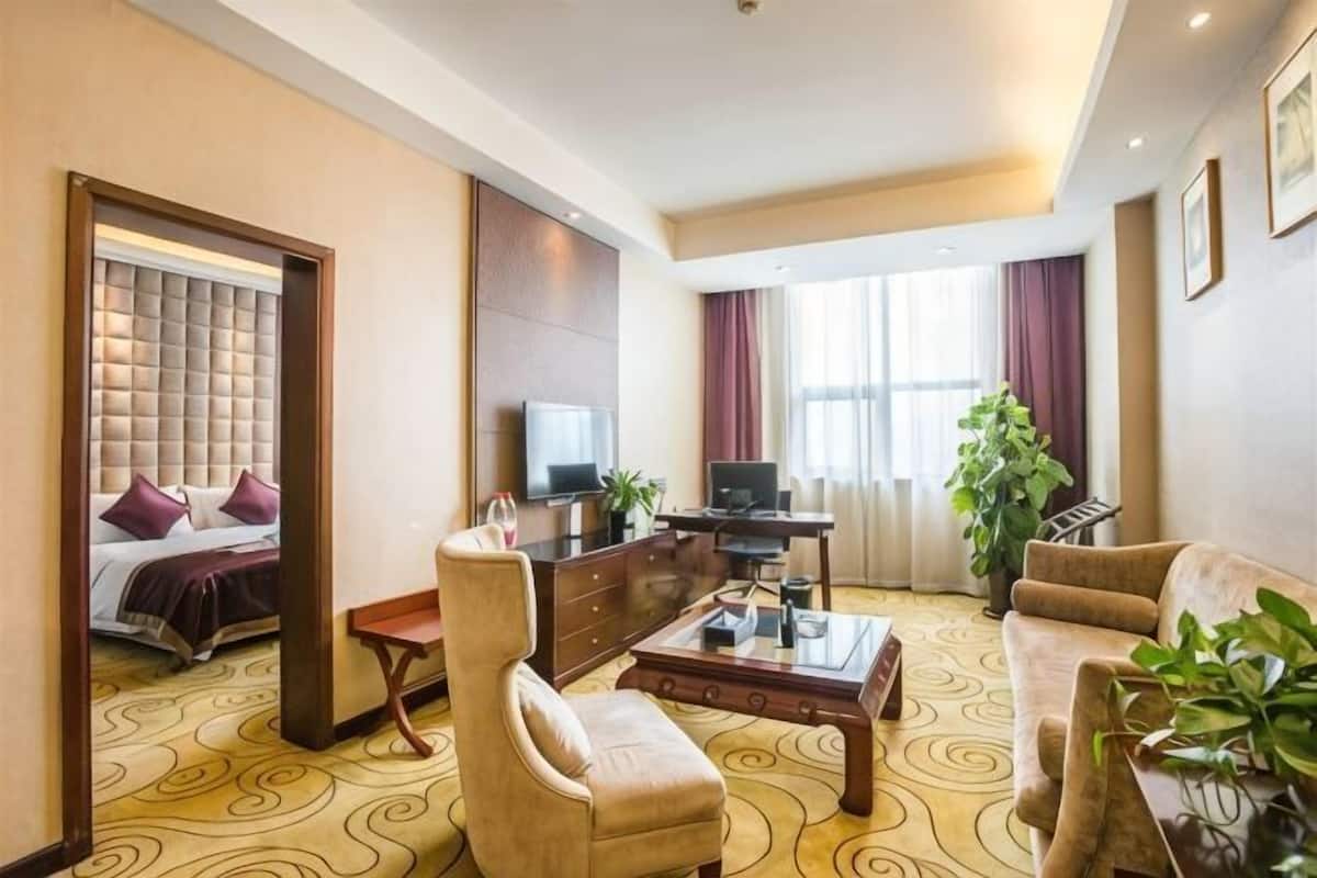 Une chambre d’hôtel équipée d’un lit, d’une télévision, d’un bureau, d’une chaise, d’un canapé et d’une grande fenêtre.