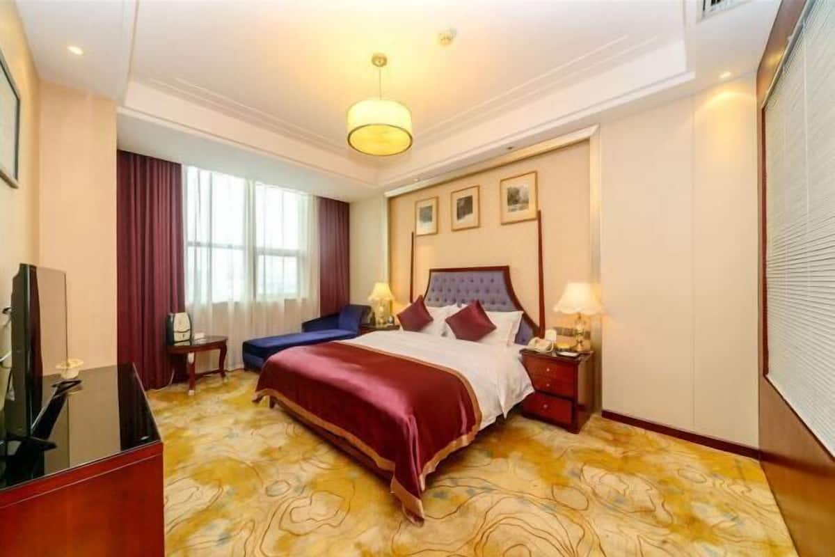 Une chambre d’hôtel avec un grand lit, un bureau, une chaise et un téléviseur.
