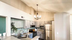 A modern kitchen with stainless steel appliances, a central island, and a hanging light fixture. - Cozy Lakeview Condo - 60 Day Special (Littleton)