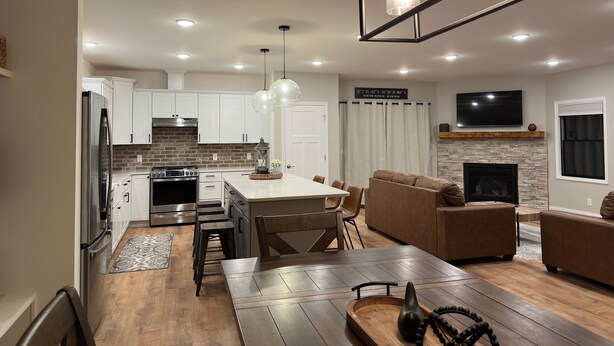 Una cocina moderna con armarios blancos, una isla central e iluminación colgante.