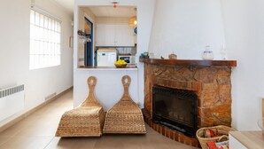 Una cocina con chimenea de piedra, taburetes de mimbre y un reloj en la pared.