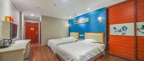 A hotel room with two beds, a desk with a chair, a TV, and a red door.