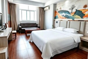 Una habitación de hotel con una cama, un sofá, un escritorio y un cuadro en la pared.