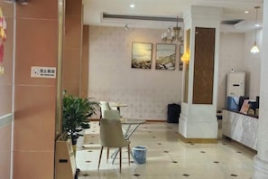 A hotel lobby with a reception desk, a seating area with chairs, a trash bin, and a potted plant. - Yanling Hotel (Meizhou)