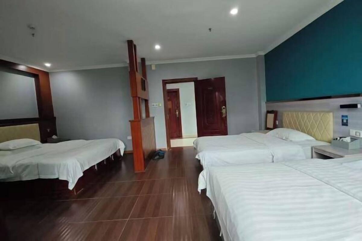 Habitación de hotel con dos camas, piso de madera, una puerta y una pared azul.