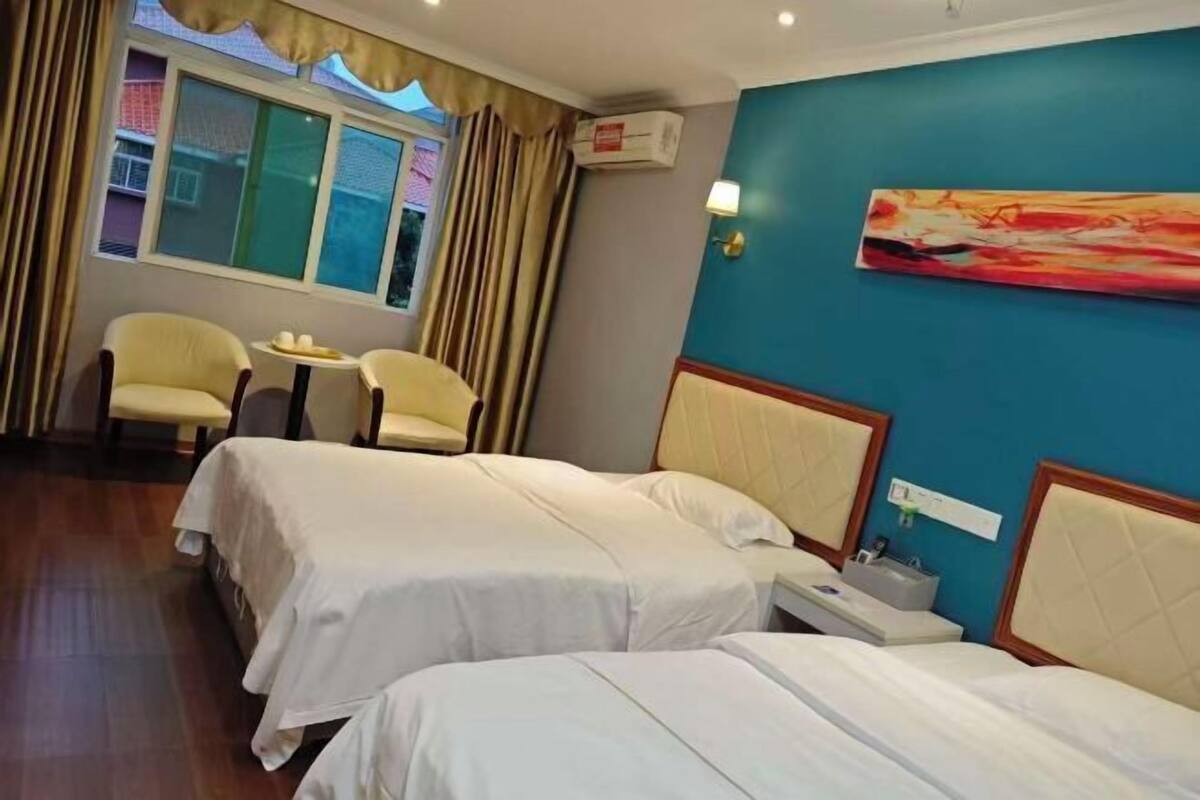 Habitación de hotel con dos camas, una mesita con sillas, un cuadro en la pared y un equipo de aire acondicionado.