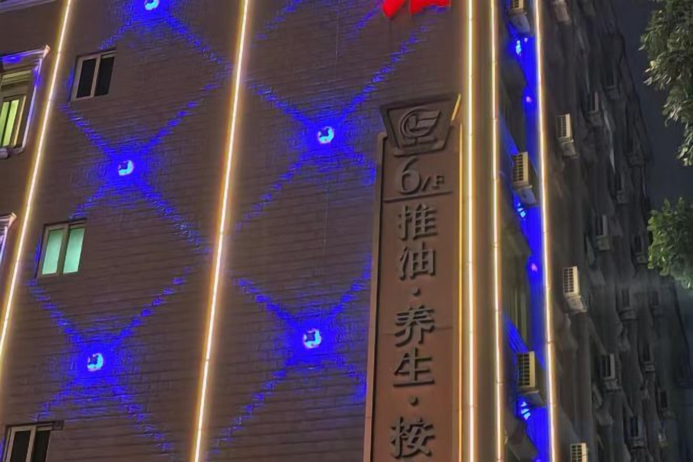 Een gevel met verlichte blauwe lijnen en een verticaal bord met Chinese karakters.