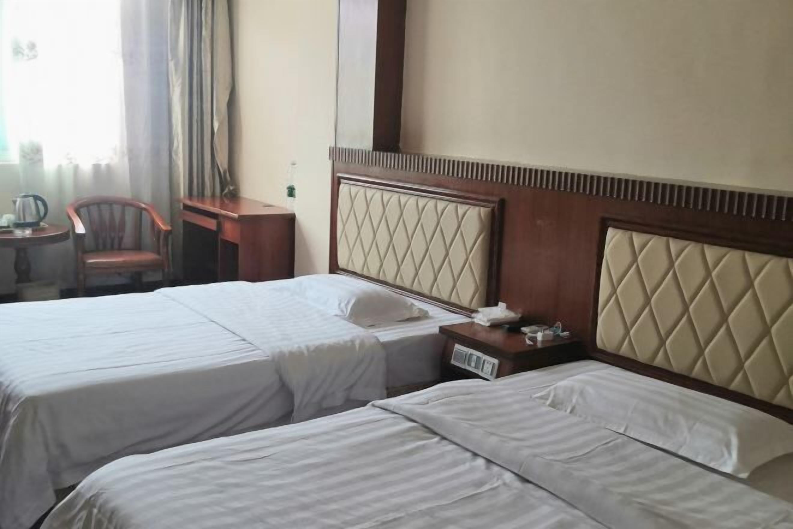 Une chambre d’hôtel avec deux lits, un bureau et une chaise.