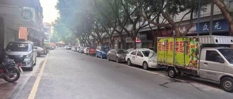 Una calle con automóviles estacionados y un camión de reparto a la derecha.