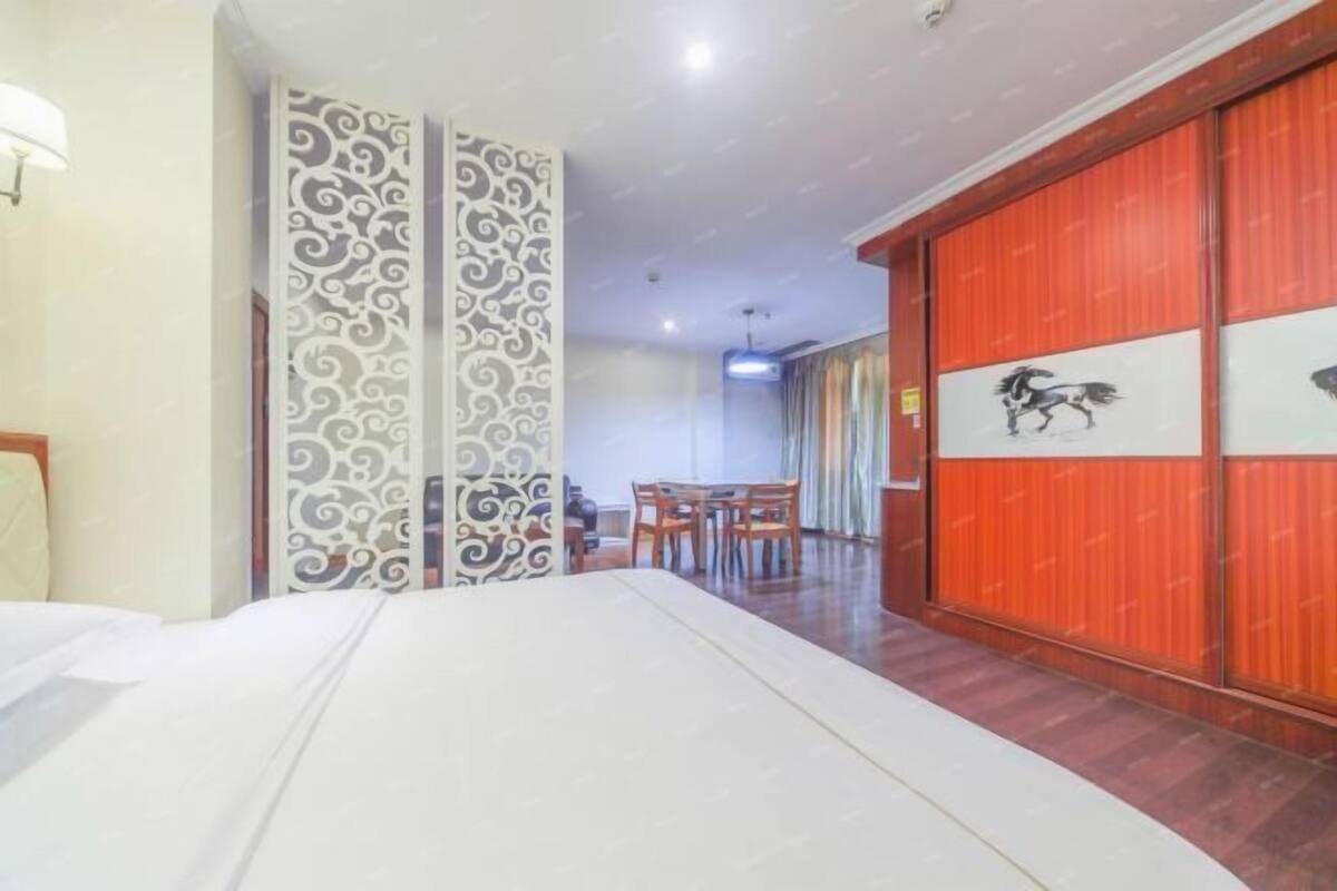 Habitación de hotel con una cama, zona de comedor con mesa y sillas, y una puerta corrediza roja con una imagen de un caballo.