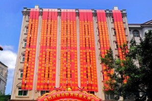 A building with multiple floors and a large banner with text. - Yanling Hotel (Meizhou)