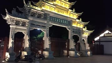 A traditional Chinese gate with intricate carvings and a golden roof, illuminated at night.