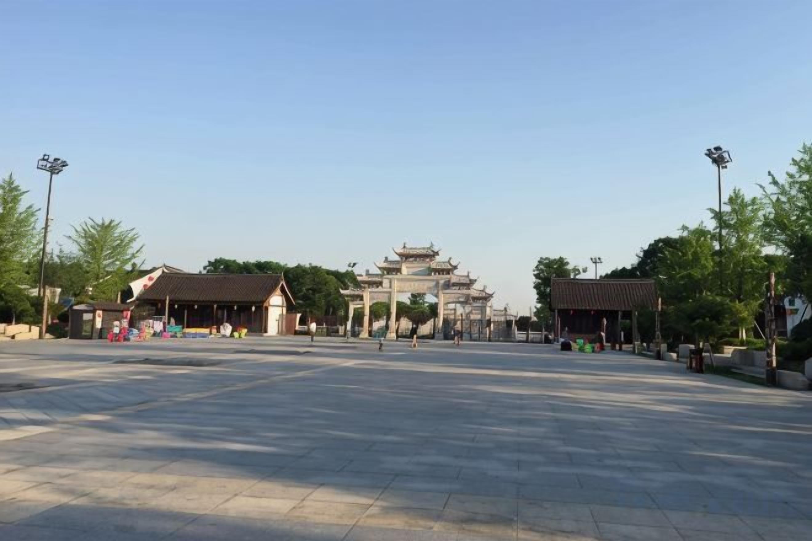 Une vaste place agrémentée d’une porte d’entrée de style traditionnel et bordée de bâtiments adjacents, probablement un site historique.