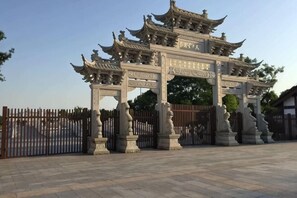 A traditional Chinese gate with intricate carvings and a clear sky. - Haining chunxi hotel (Haining)