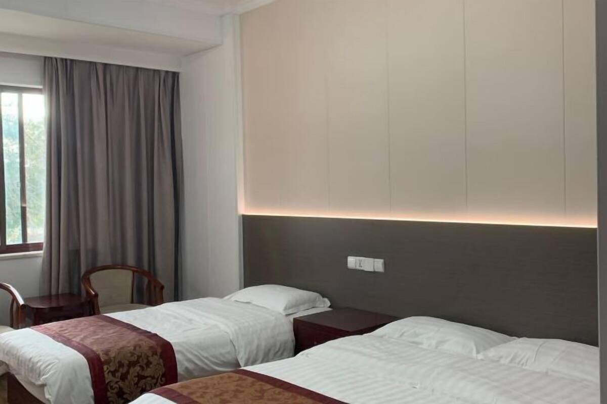 Una habitación de hotel con dos camas, un escritorio, una silla y una ventana con cortinas.