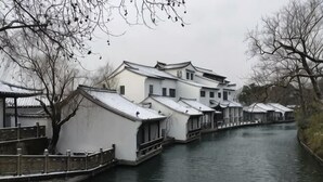Ein traditionelles Gebäude mit einem Giebeldach, einem Kanal und einer Holzbrücke.
