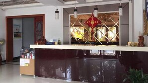 A reception area with a counter, a decorative window, and a ceiling with recessed lighting. - Haining chunxi hotel (Haining)
