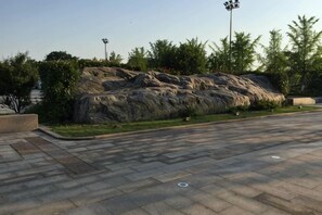 A paved walkway with a landscaped rock feature and greenery. - Haining chunxi hotel (Haining)