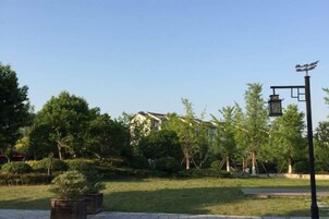 Un parque con cielo despejado, árboles, una farola y un edificio al fondo.