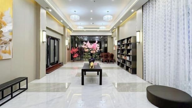 A hotel lobby with a polished floor, a reception desk, a seating area, and a bookshelf. - Jinpai Hotel (Baise Xiangyang) (Baise)