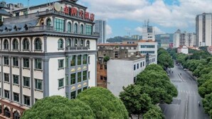 A multi-story building with a traditional architectural style, featuring a prominent entrance with a tiled roof and a pagoda-like structure on top. - Jinpai Hotel (Baise Xiangyang) (Baise)