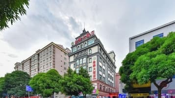 A multi-story hotel with a prominent sign, surrounded by trees and other buildings.