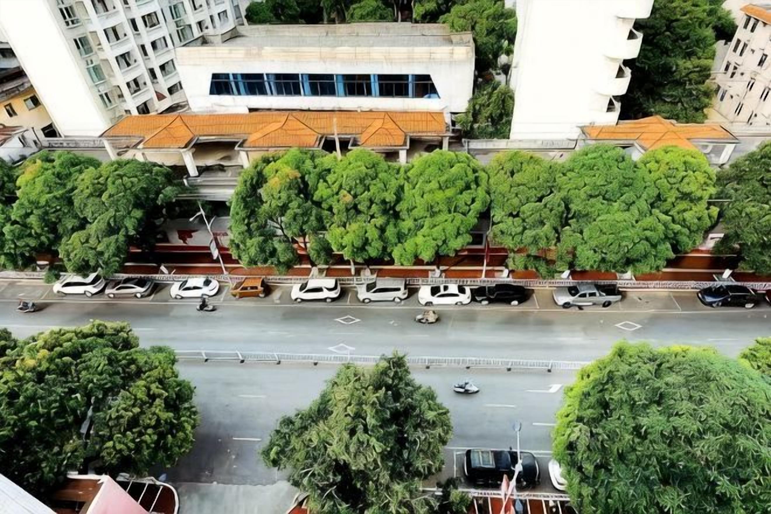 A multi-story building with a flat roof and a parking area in front.
