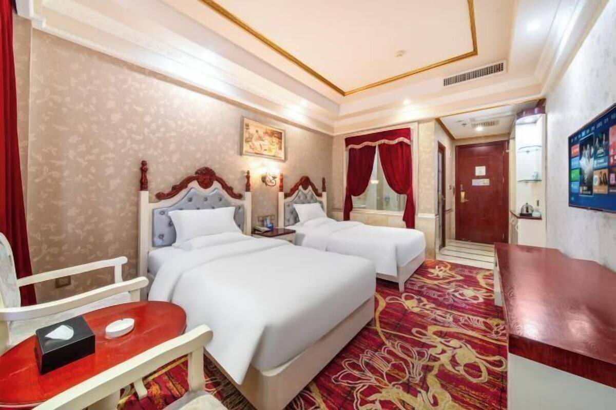 A hotel room with two beds, a desk, and a red chair.