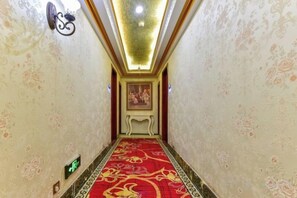 Un passadís amb una catifes amb dibuixos, un llum fixada a la paret i una obra d'art emmarcada.