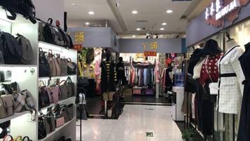 Uma loja com prateleiras cheias de bolsas e araras de roupas com manequins.