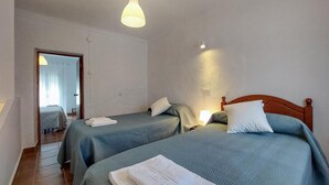 A room with two beds, each with a pillow and a folded towel. There is a door leading to another room, and a light fixture above the beds. - 2 bedroom gorgeous home in Algodonales (Algodonales)