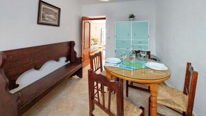 A dining area with a round glass table, wooden chairs, a wooden bench, and a light blue cabinet. - 2 bedroom gorgeous home in Algodonales (Algodonales)