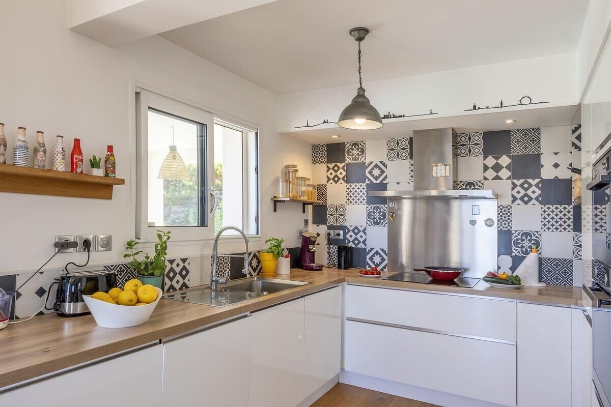 Une cuisine moderne dotée d’une grande fenêtre, d’un luminaire suspendu et de divers appareils de cuisine.