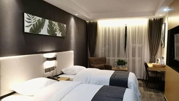 Une chambre d’hôtel avec deux lits, un bureau, une chaise, une télévision et une fenêtre avec des rideaux.