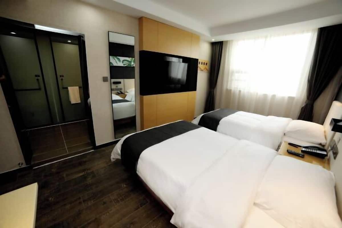 A hotel room with two beds, a TV, a mirror, and a wooden panel wall.