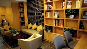 Un salon moderne comprenant un canapé, des fauteuils, une table basse et une bibliothèque remplie de livres et de plantes.