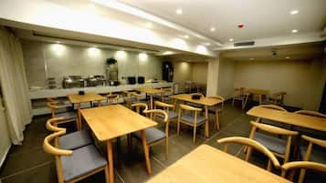 A dining area with multiple tables and chairs, a kitchen area with appliances, and a counter.