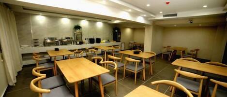 A dining area with multiple tables and chairs, a kitchen area with appliances, and a counter.