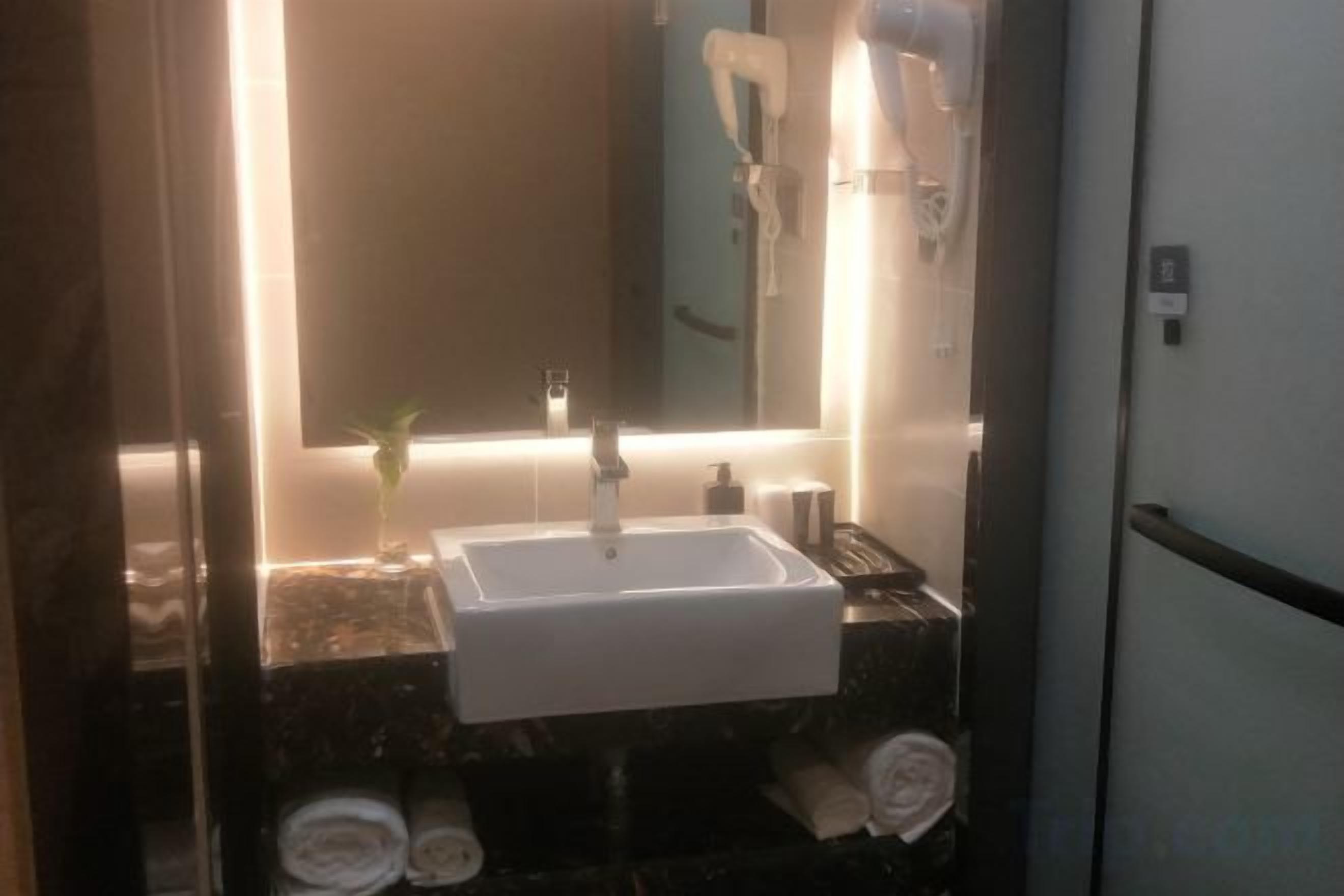 Ein Badezimmer mit Waschbecken, Spiegel, Handtuchhalter und Fön.