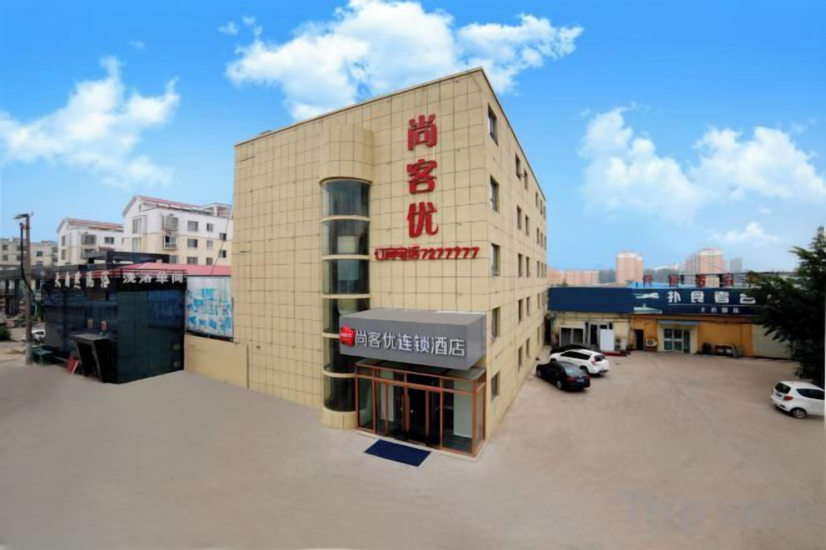 A hotel with a prominent red sign, a parking lot, and a clear sky.