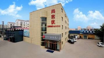 A hotel with a prominent red sign, a parking lot, and a clear sky.