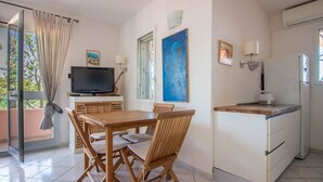 A modern kitchen with a dining area, a television, and artwork on the walls.