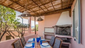 An outdoor dining area with a table set for four, a grill, and a view of the surrounding landscape.