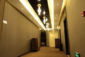 A hotel corridor with overhead lighting, a trash bin, and a door at the end. - Daqing fashion impression Theme Hotel (Daqing)
