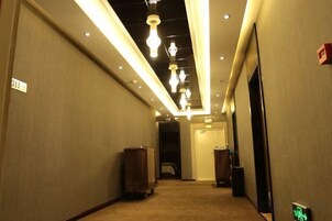 Un pasillo de hotel con iluminación en el techo, un basurero y una puerta al final.