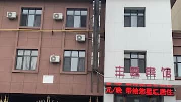 A building with multiple windows and air conditioning units. There is a sign with red text on the building.
