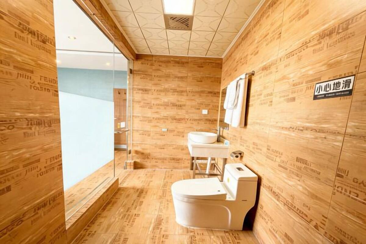 A modern bathroom with wooden paneling, a toilet, sink, and a mirror.