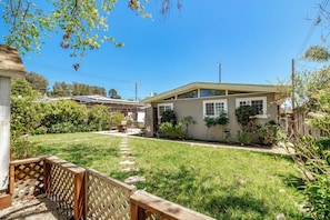 A residential property with a well-maintained lawn, a wooden deck, and a house with a gabled roof. - 3 Bedroom House - 3 min from beach! (La Selva Beach)