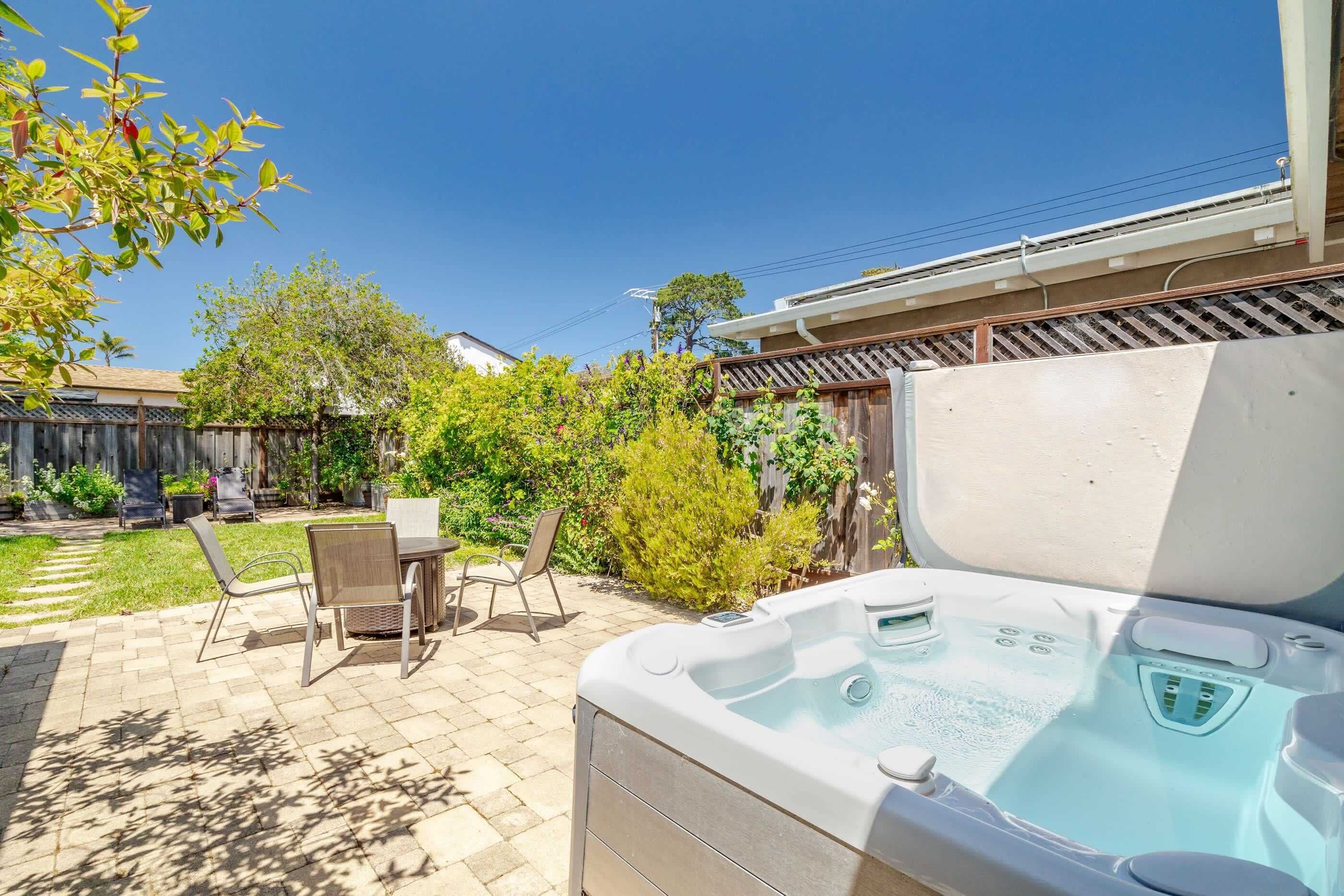 A backyard with a hot tub, patio furniture, and a wooden fence.
