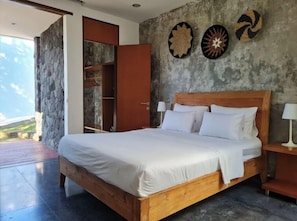 A bedroom with a wooden bed, a wardrobe, and a stone wall.